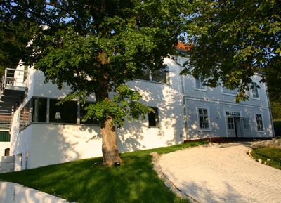 Fehér villa nagy ablakokkal és egy fával az előtérben.