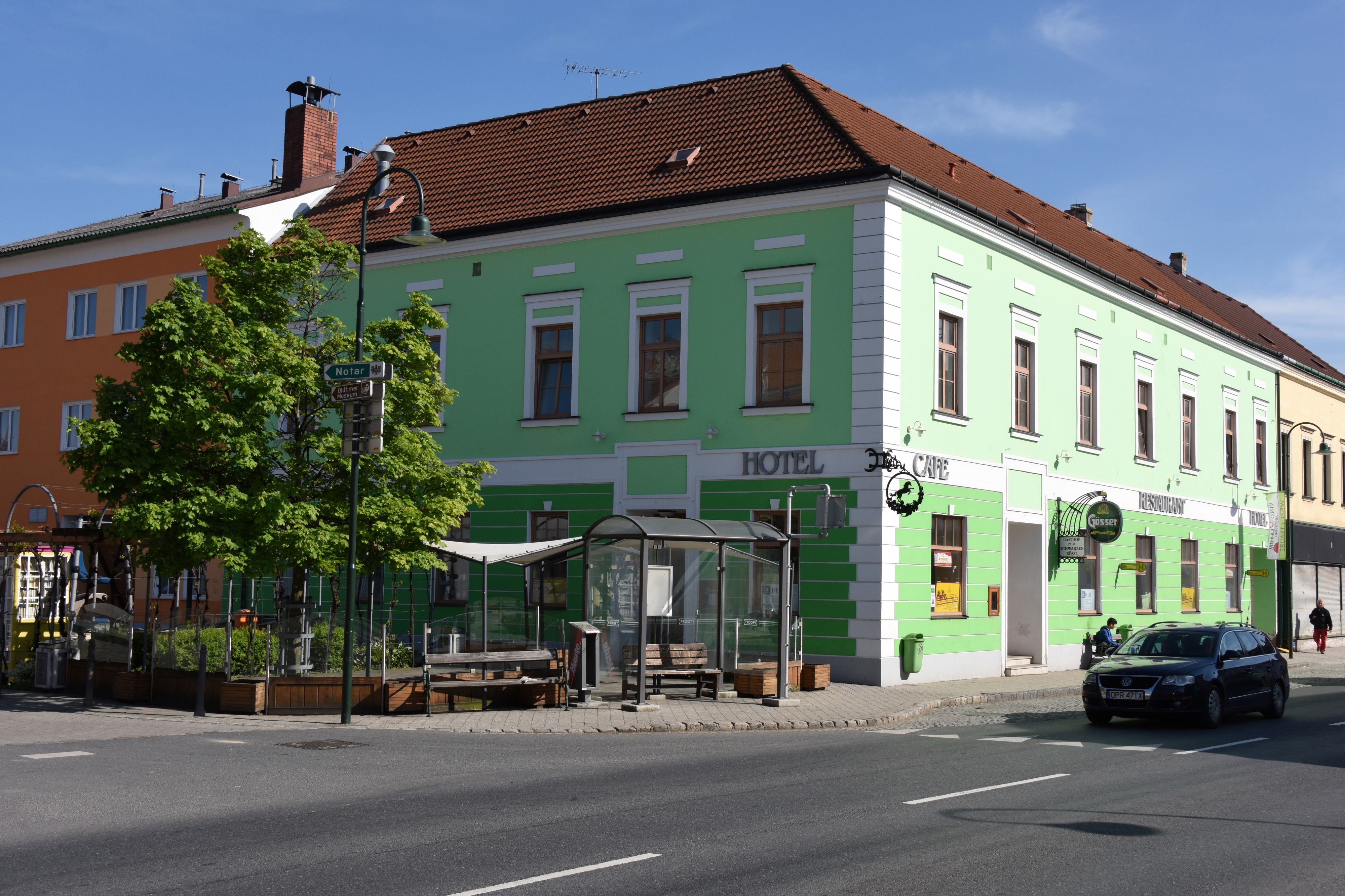 Zöld épület szálloda és kávézó táblákkal egy utcasarkon.