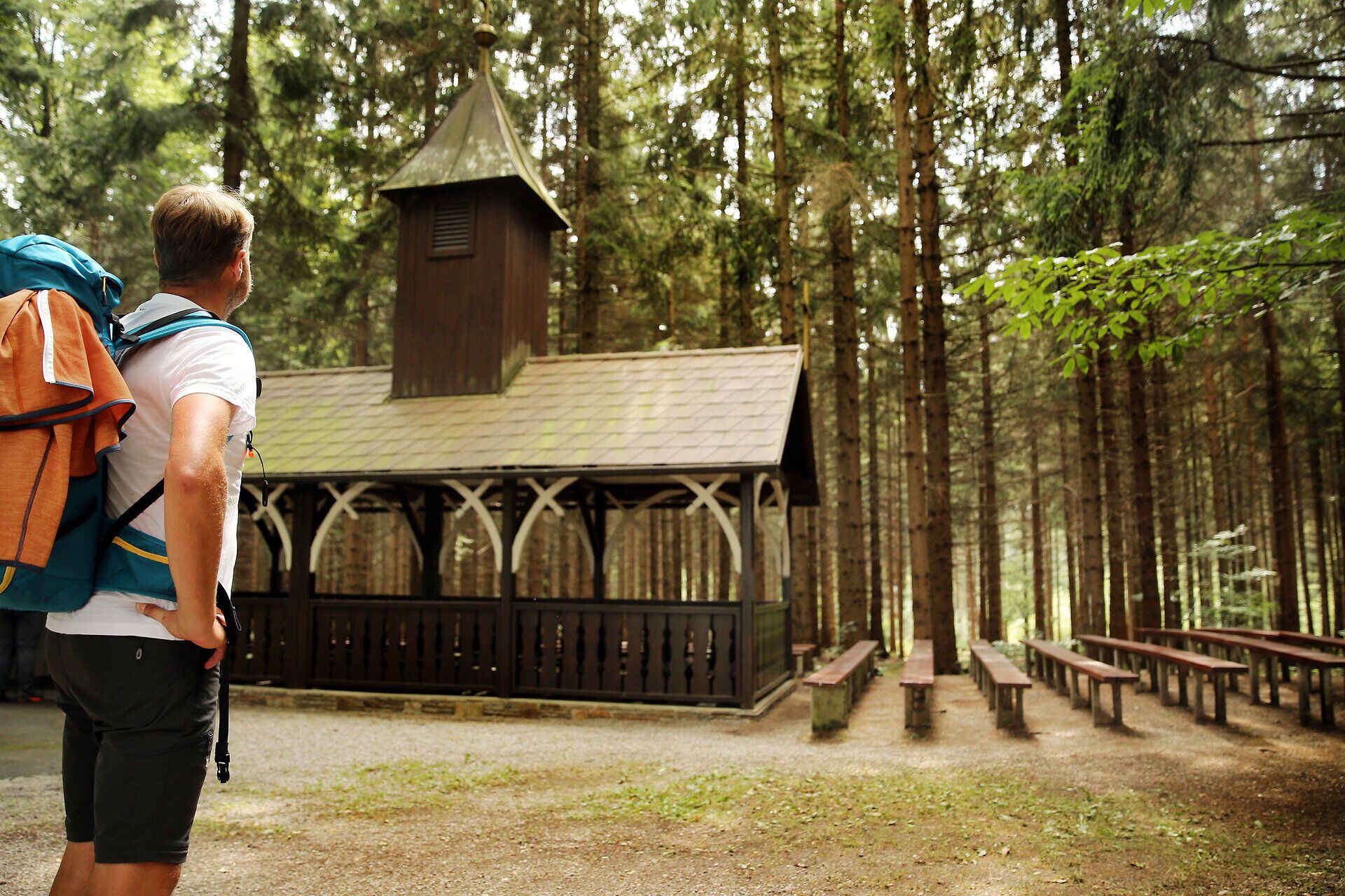 Egy zarándok megcsodál egy fatemplomot az erdő közepén.