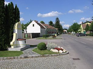 Mitterndorf an der Fischa utcája házakkal és emlékművel.