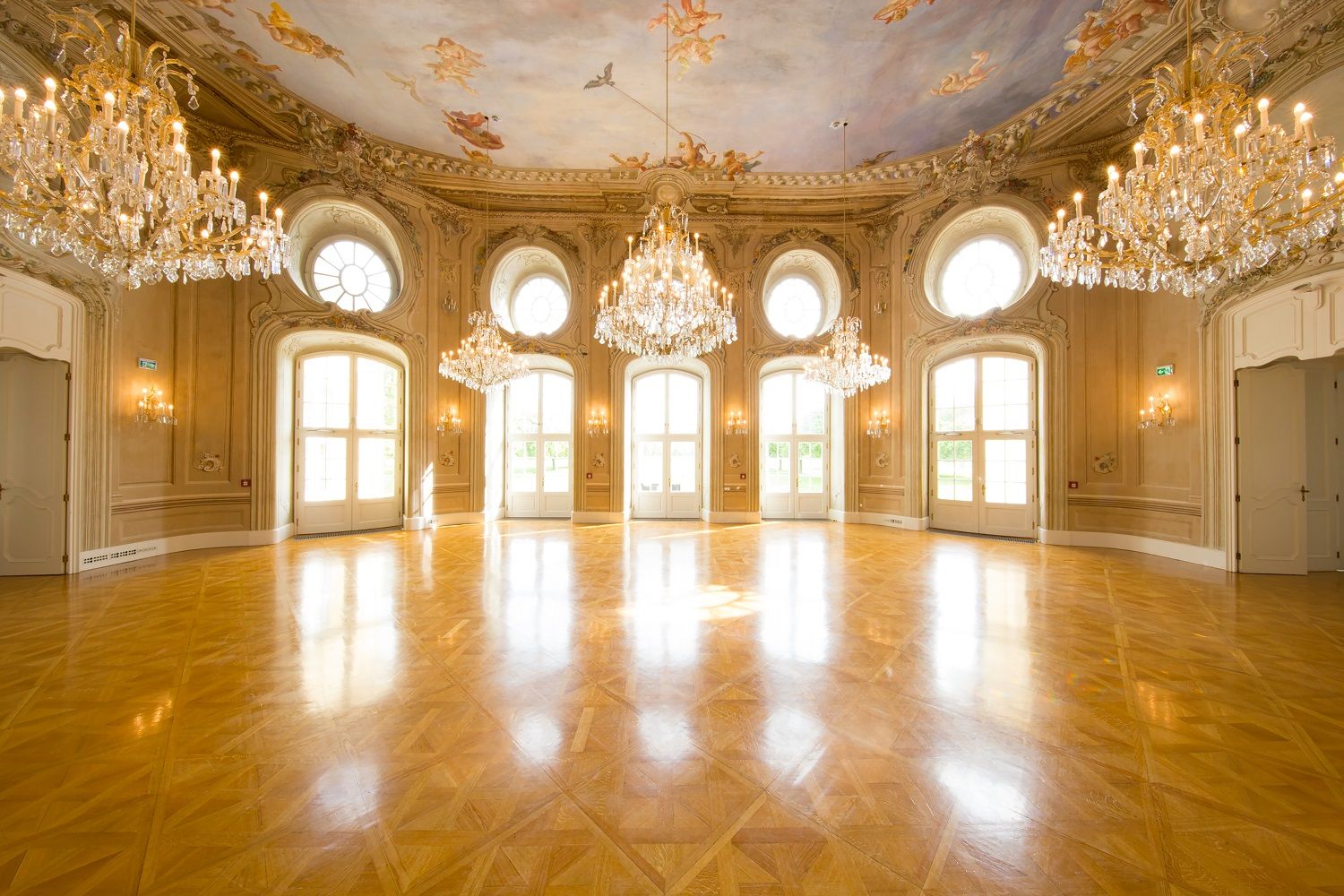 Elegáns bálterem csillárokkal és festett mennyezettel a Laxenburgi Konferencia Központban.