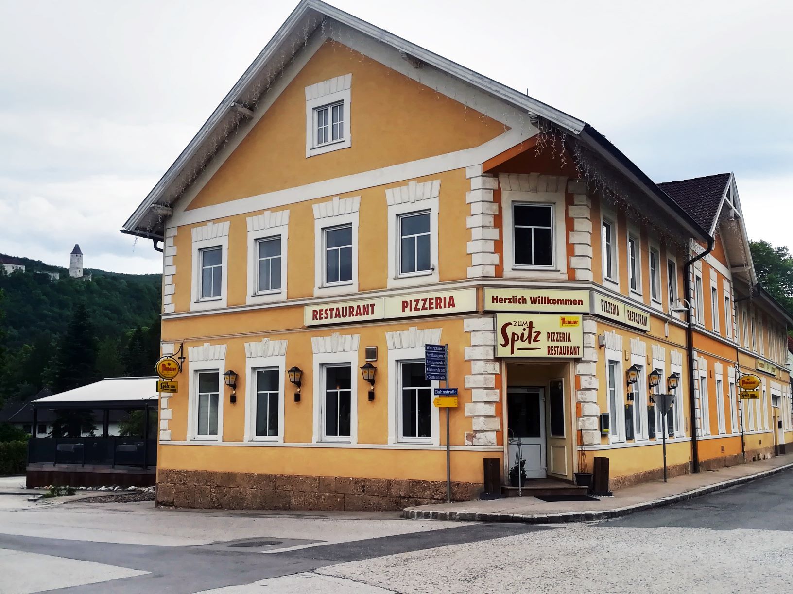 Sárga színű épület "Restaurant Pizzeria Zum Spitz" felirattal.