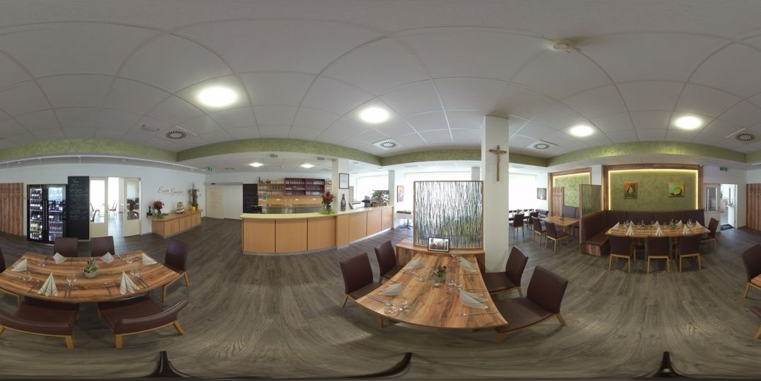 Egy modern étterem belső nézete, fa asztalokkal és székekkel, növényekkel és a falakon művészeti alkotásokkal díszítve.