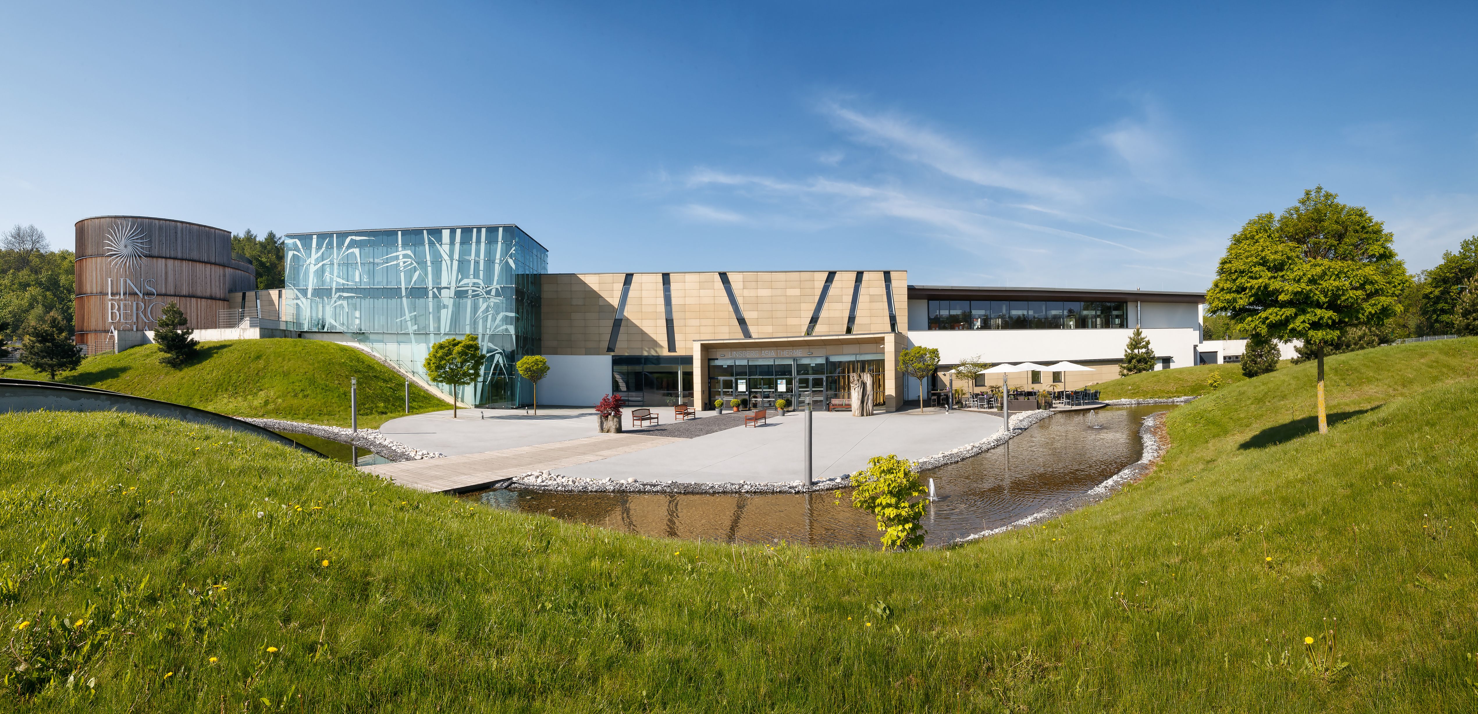A Linsberg Asia Therme külső nézete a modern építészet és a zöldterületek látványával.