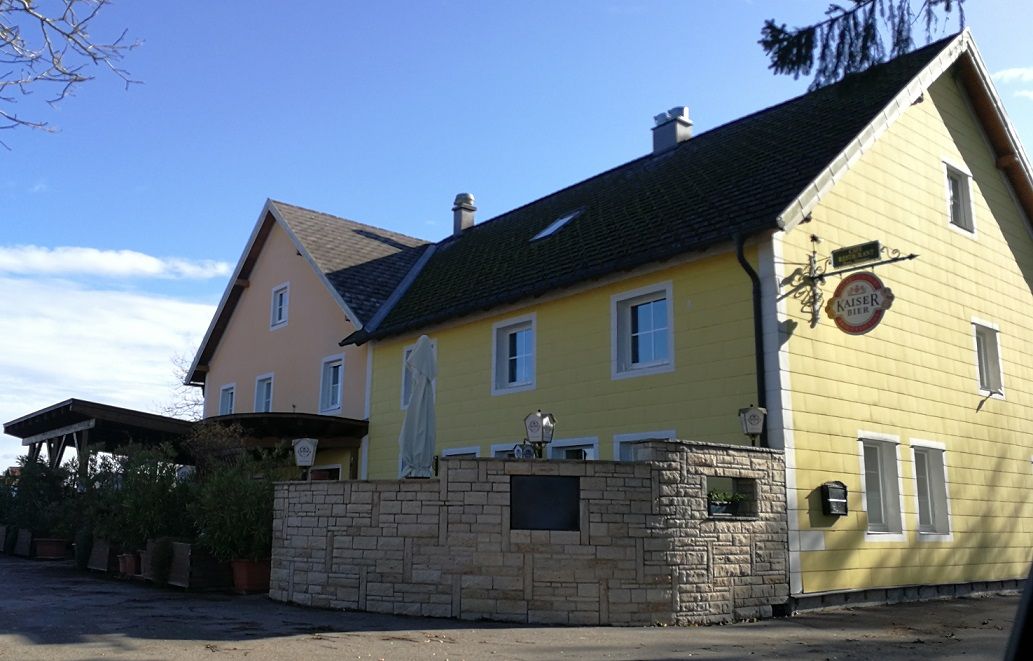 Sárga vidéki vendéglő Kaiser Bier felirattal és napernyővel az előtérben.