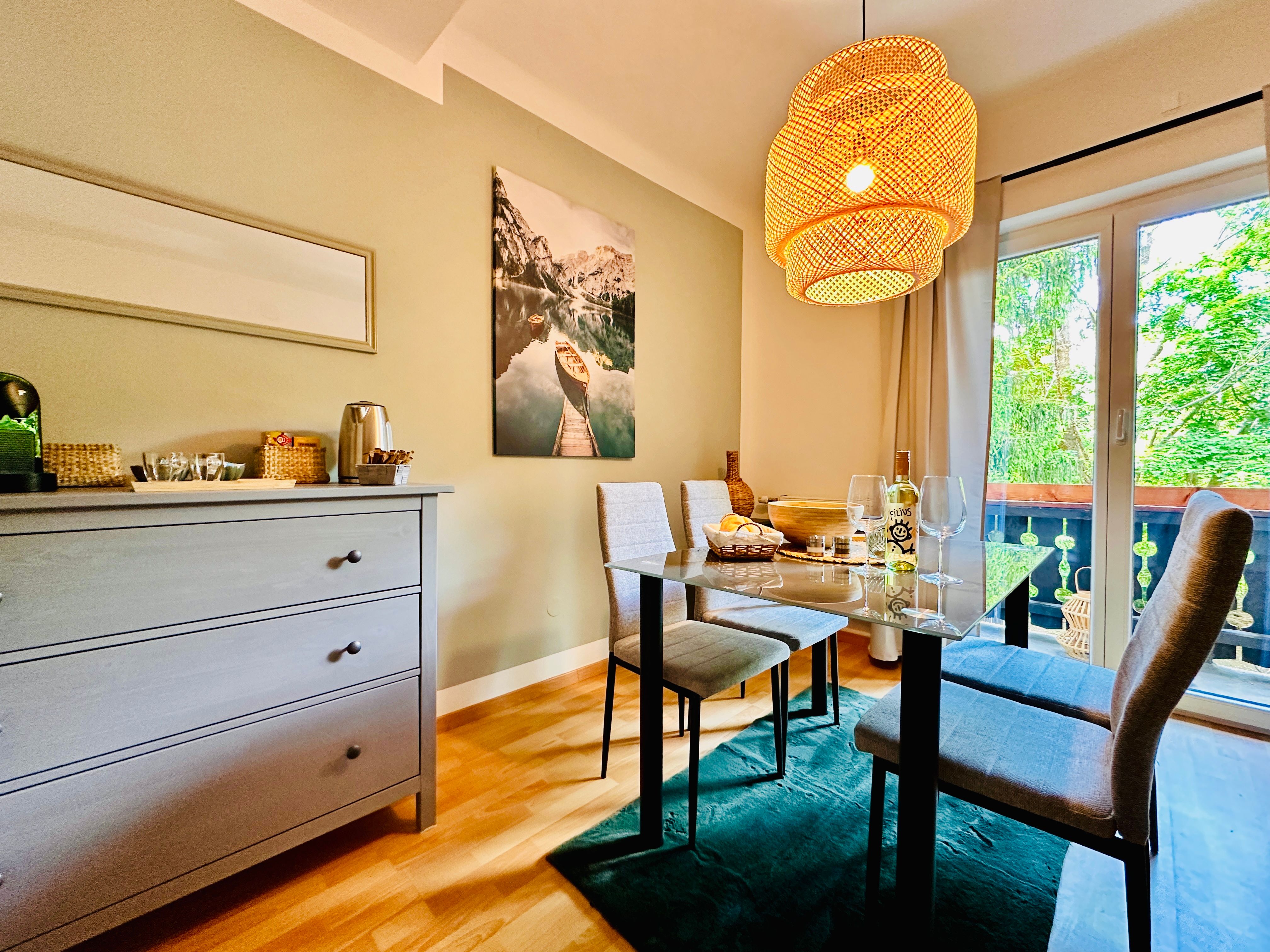 Hangulatos étkező asztallal, székekkel és függőlámpával, kilátással az erkélyre és a természetre.