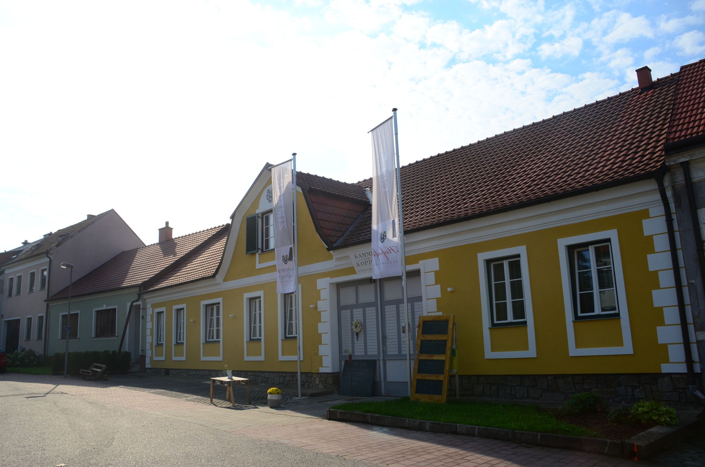 Sárga épület piros tetőcserepekkel és két zászlóval előtte.