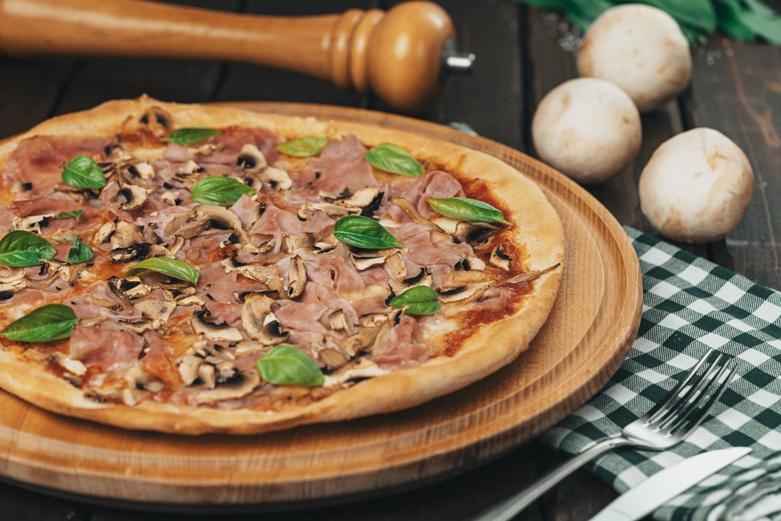 Sonkás, gombás, bazsalikomos pizza fatáblán.