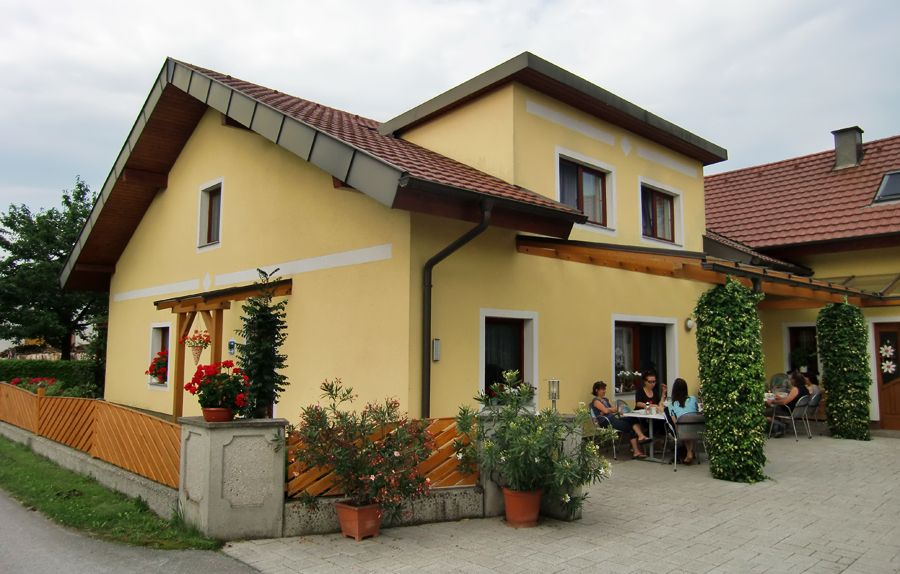 Sárga ház terasszal és kint ülő emberekkel.