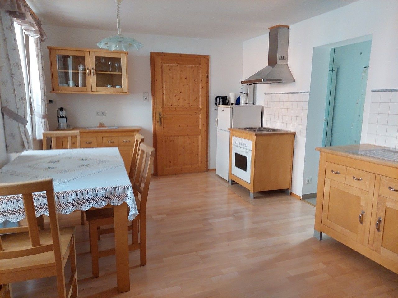 Nappali-konyha fabútorokkal, étkezőasztallal, székekkel, tűzhely, hűtőszekrény és faliszekrény.