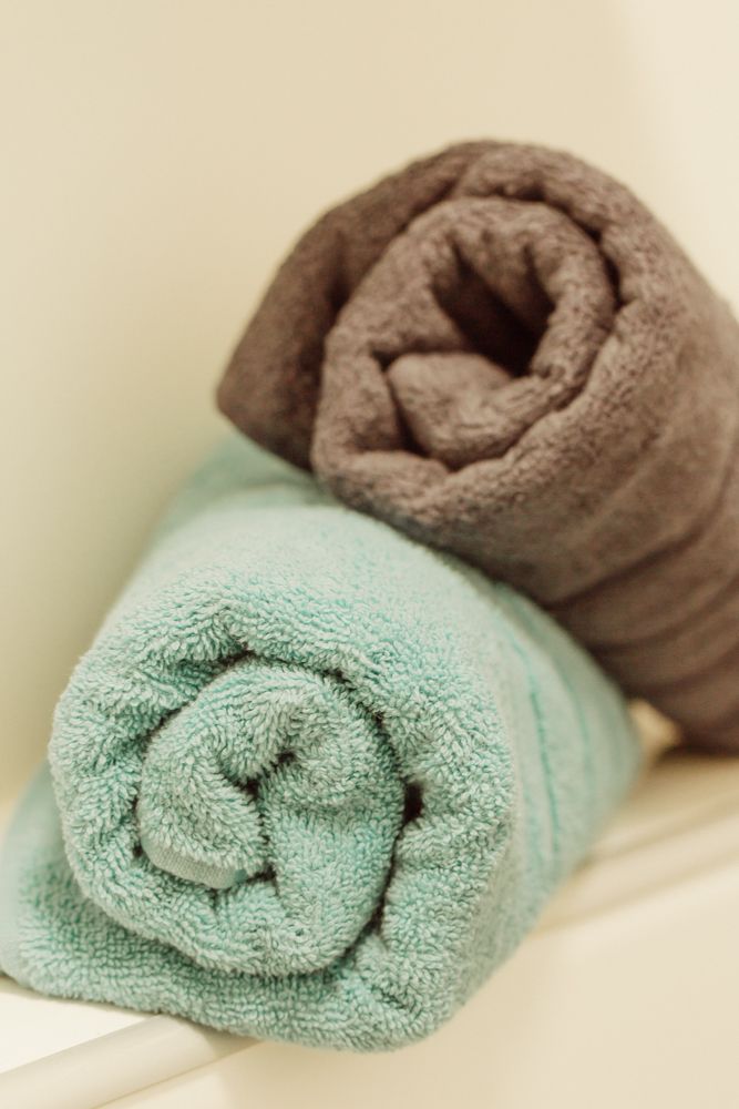 Két feltekert törülköző, egy türkizkék és egy barna színű, fekszik a polcon.