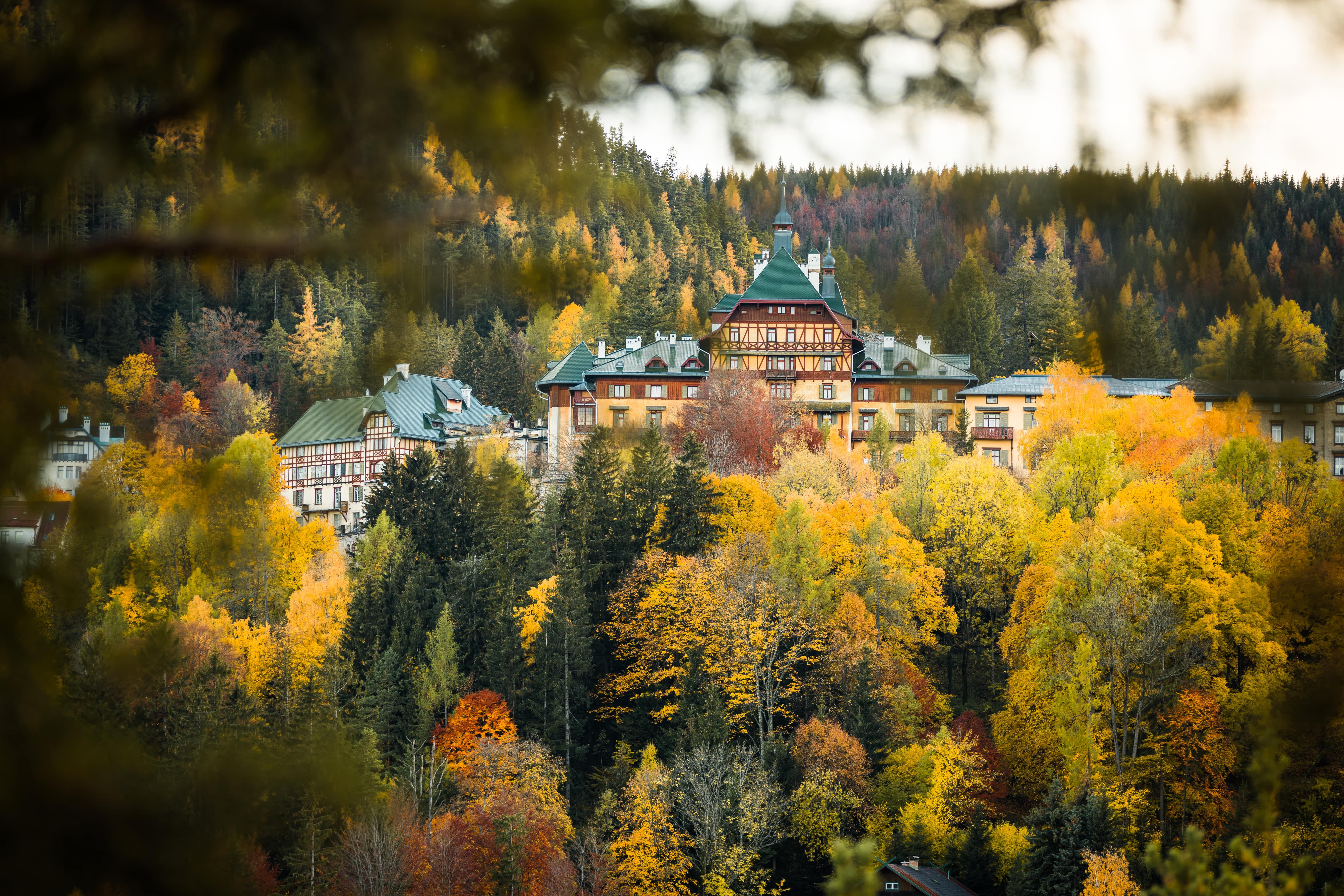 Südbahnhotel Semmering ősszel, színes lombhullató erdőkkel körülvéve.