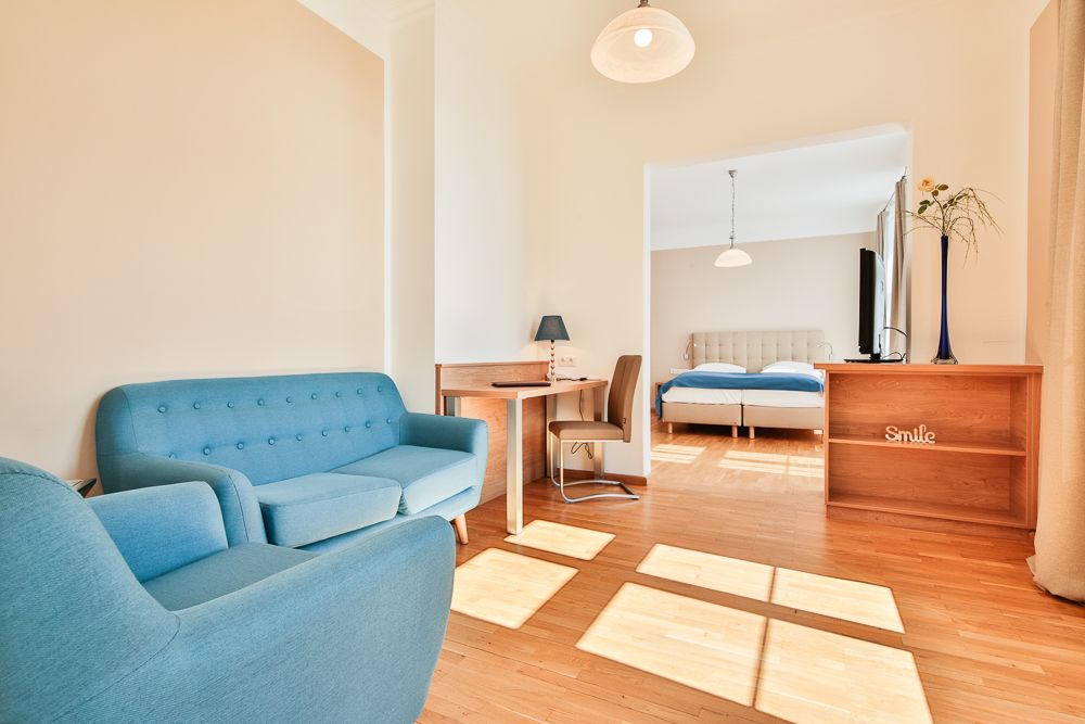 Világos szállodai szoba kék bútorokkal és franciaággyal.