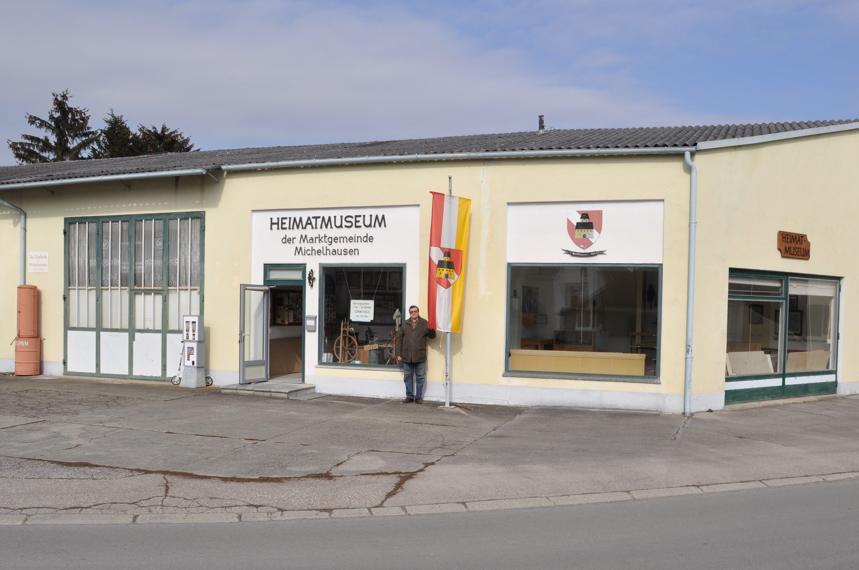 A Michelhauseni Helytörténeti Múzeum külső képe sárga épülettel és zászlóval.