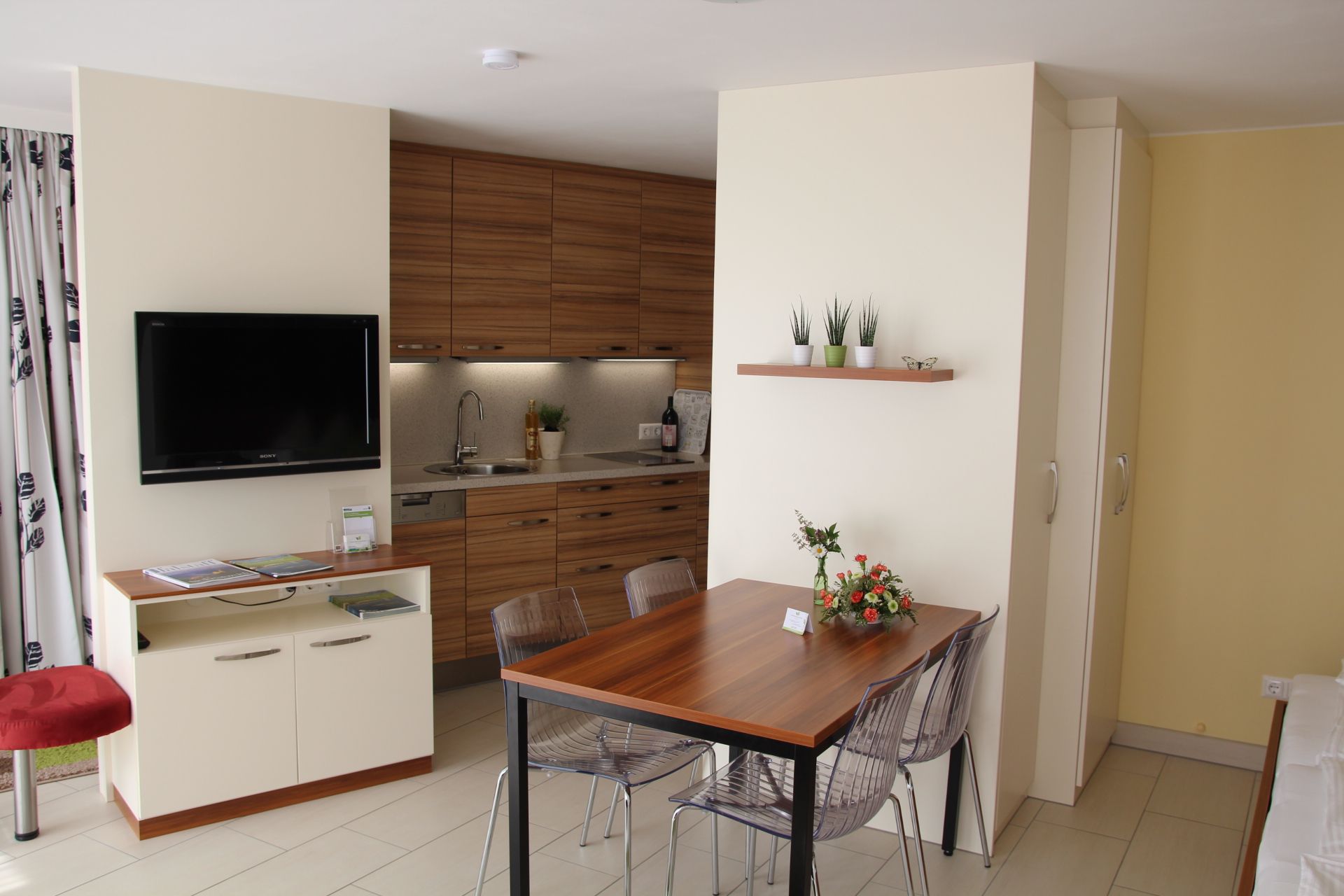 Modern kerti lakás konyhával, étkezőasztallal és TV-vel.