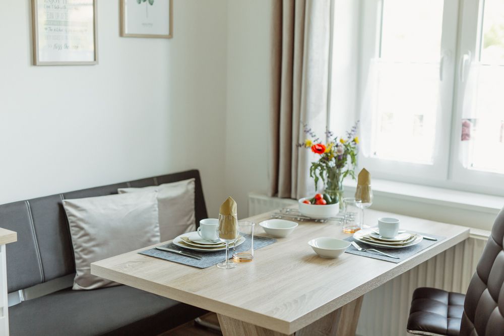 Étkező egy modern lakásban, terített asztallal és virágokkal.