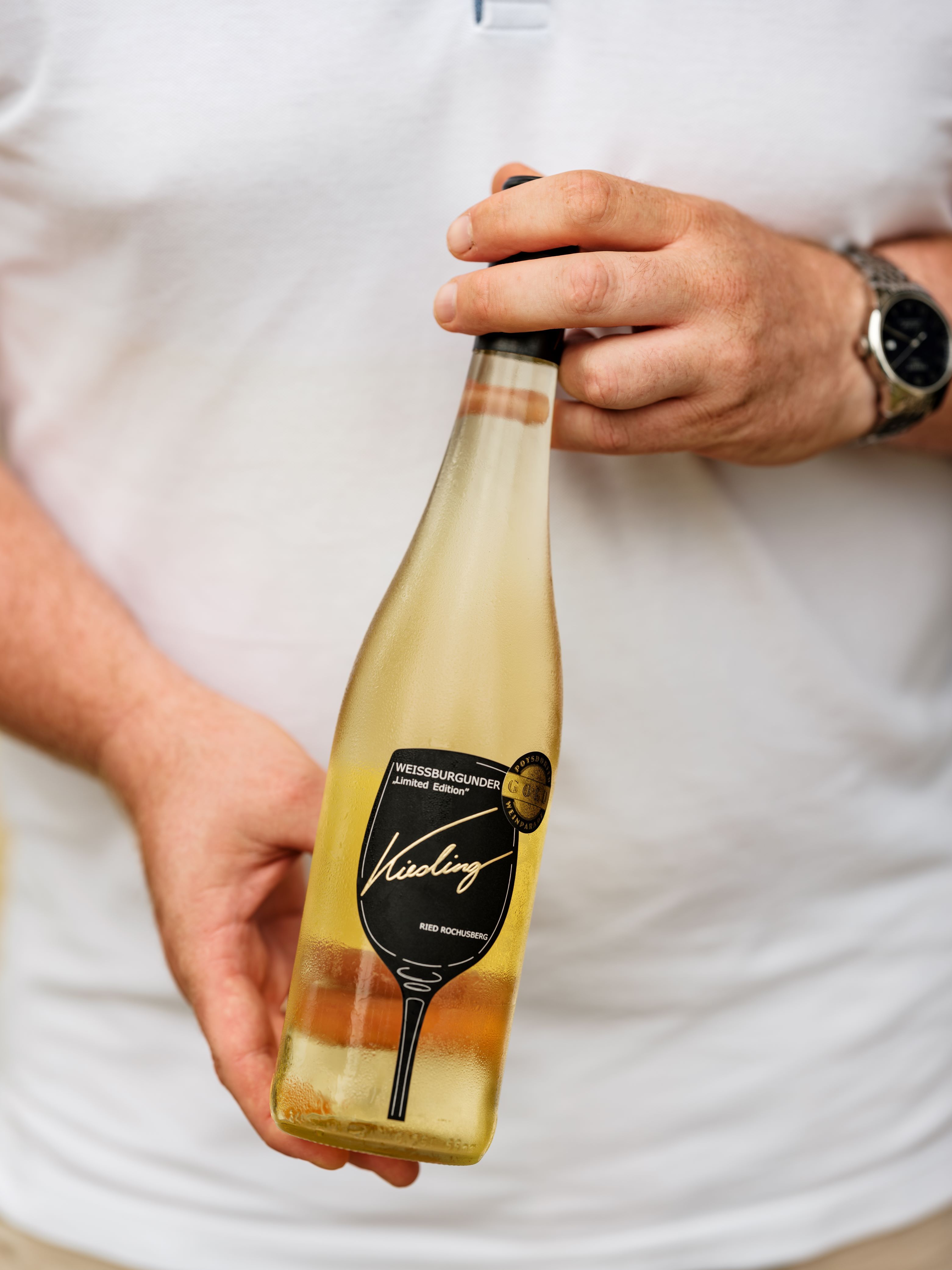 A Kiesling pincészet Pinot Blanc palackját tartó személy.