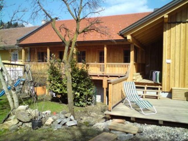 Fából készült épület terasszal és kerttel az előtérben.