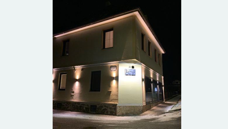 Éjszaka kivilágított épület a "Haus Zwei" felirattal.