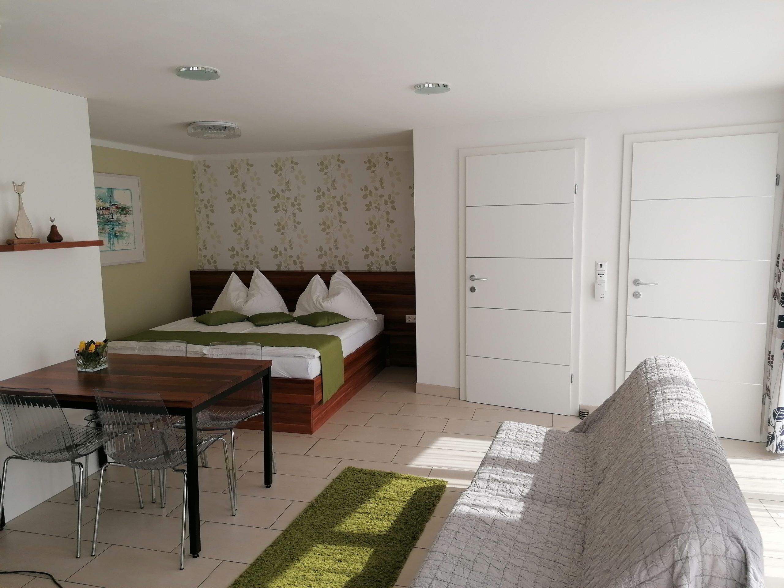 Szoba franciaággyal és két fehér bejárati ajtóval