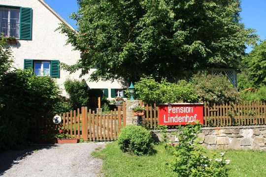 Egy ház kerttel és egy "Pension Lindenhof" felirattal a fakerítésen.