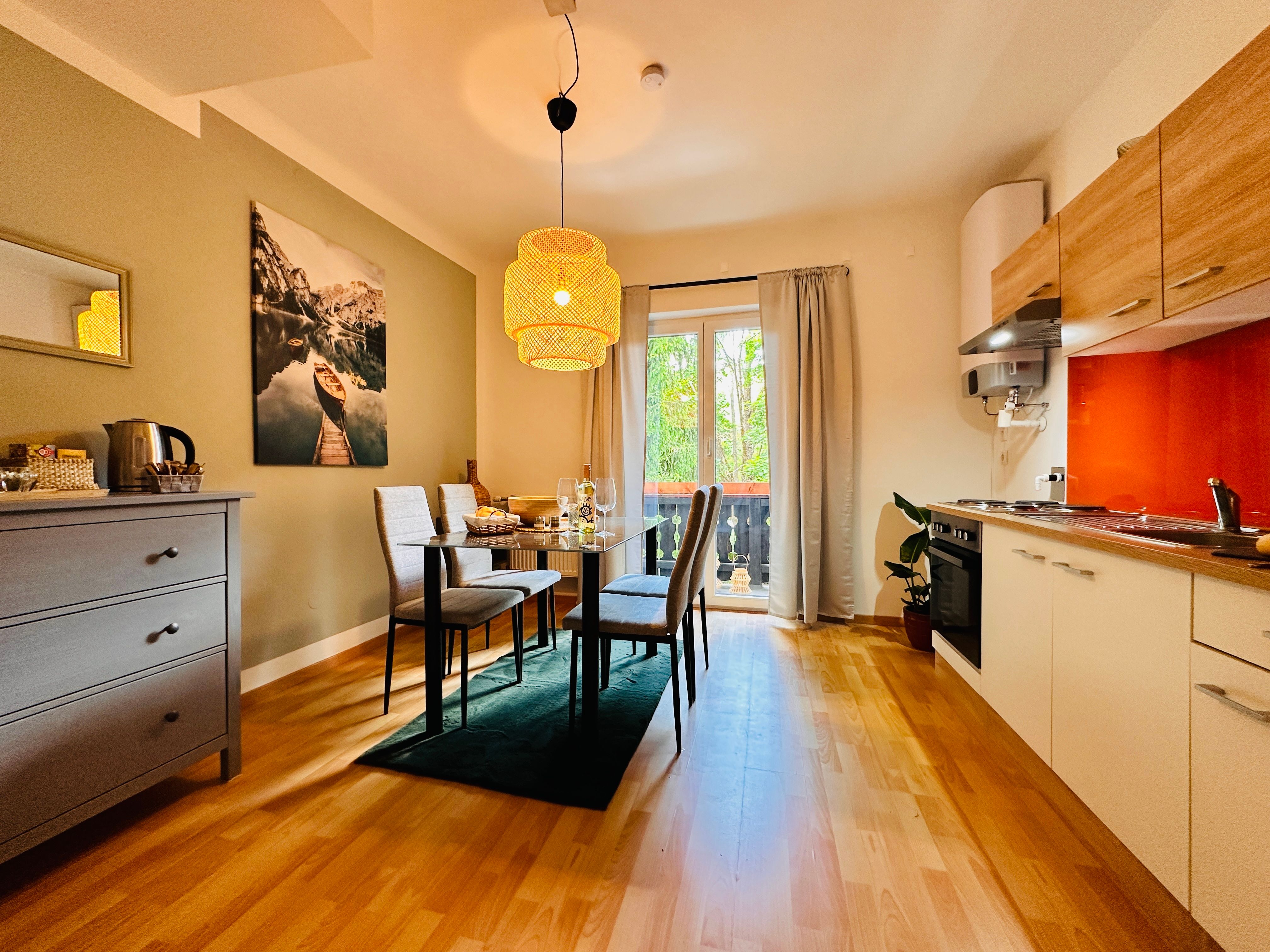 Hangulatos lakás étkezőasztallal, székekkel, konyhasarokkal és erkéllyel.