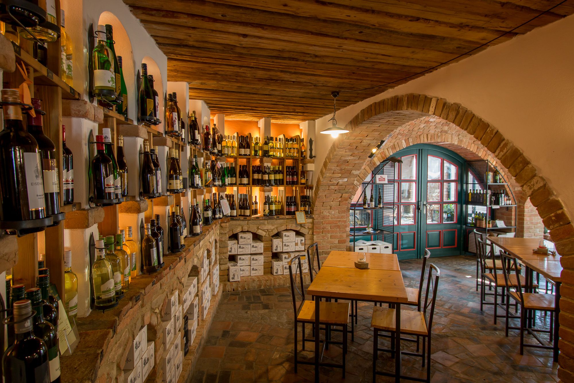 Borospince borosüvegekkel teli polcokkal, faasztalokkal és téglaboltozatokkal.