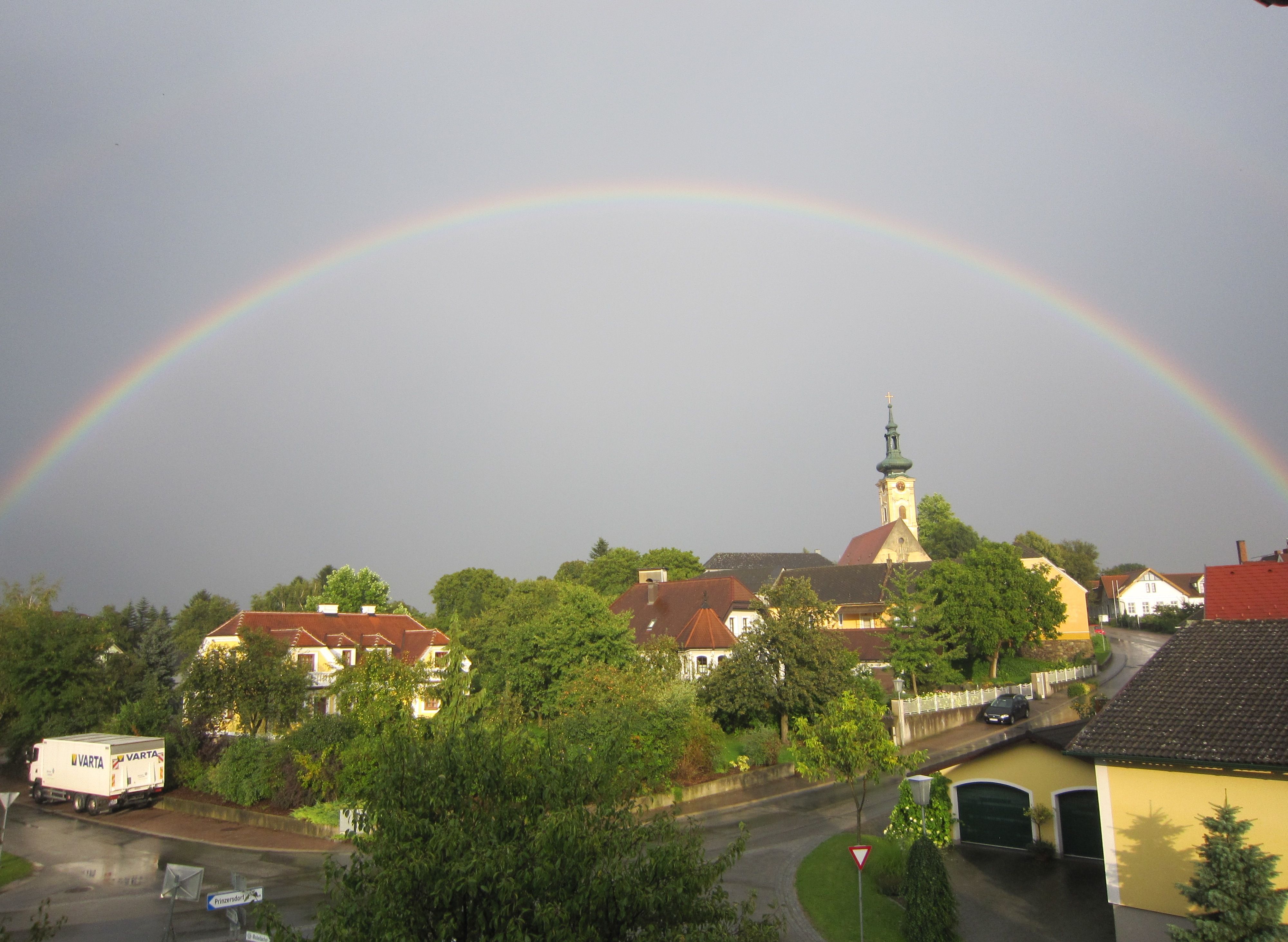 Egy szivárvány húzódik egy templomos és házas falu fölött Gerersdorfban.