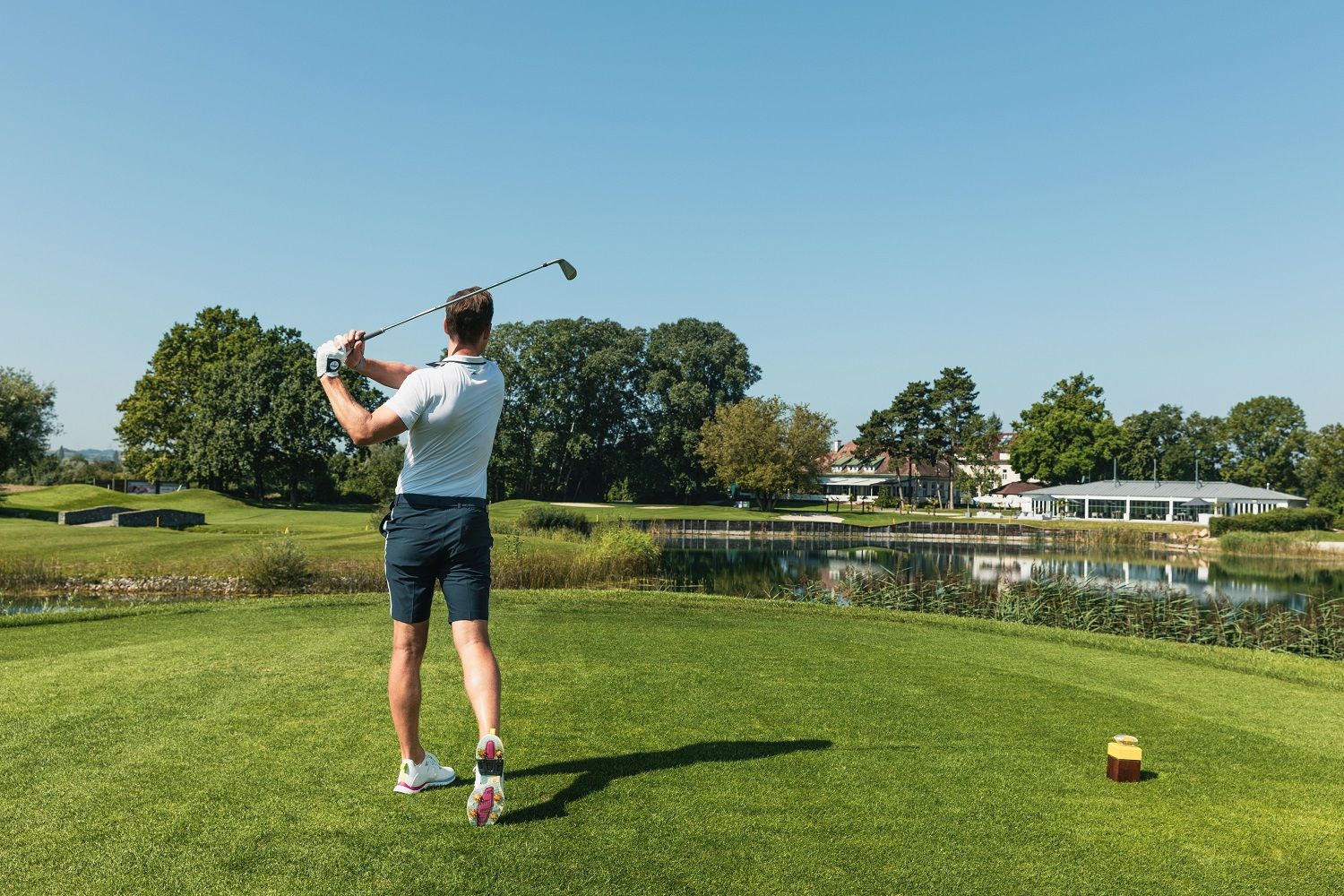 Golfozó, kezében golfütővel, golfozik.