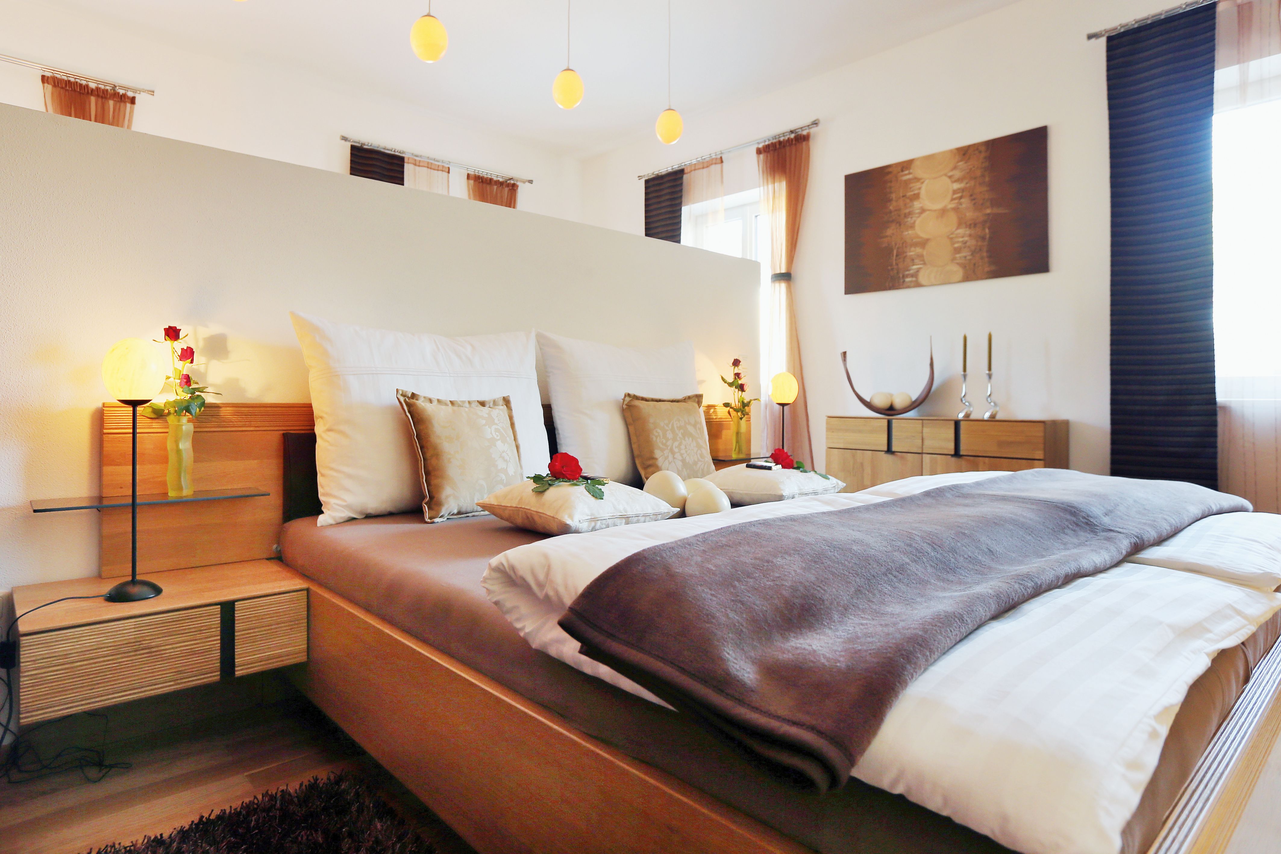 Hangulatos hálószoba franciaággyal, párnákkal és rózsákkal díszített, fából készült bútorokkal és lágy világítással.