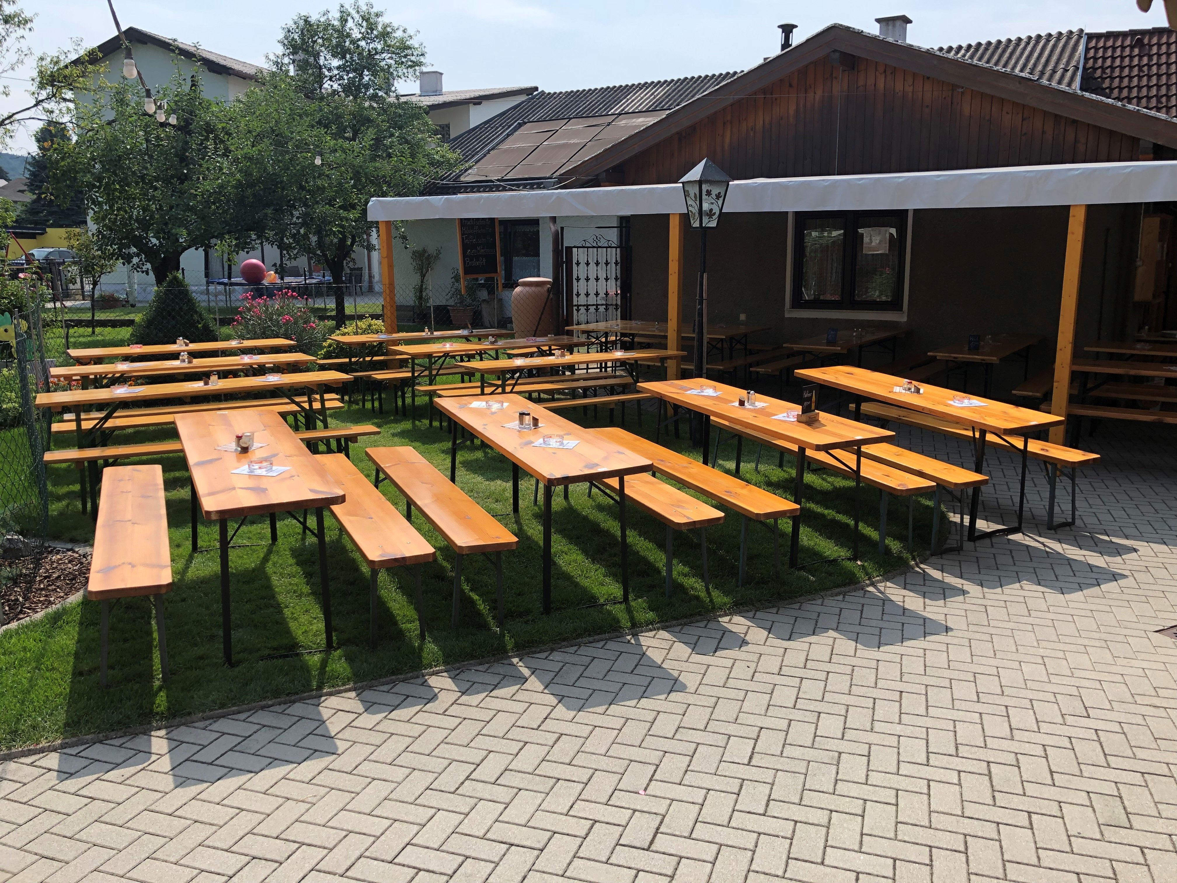 Fapadok és asztalok egy borozó kertjében, napvédelemmel.