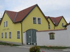 Sárga épület piros tetővel és zöld kapuval, felirattal: "Vendégház".