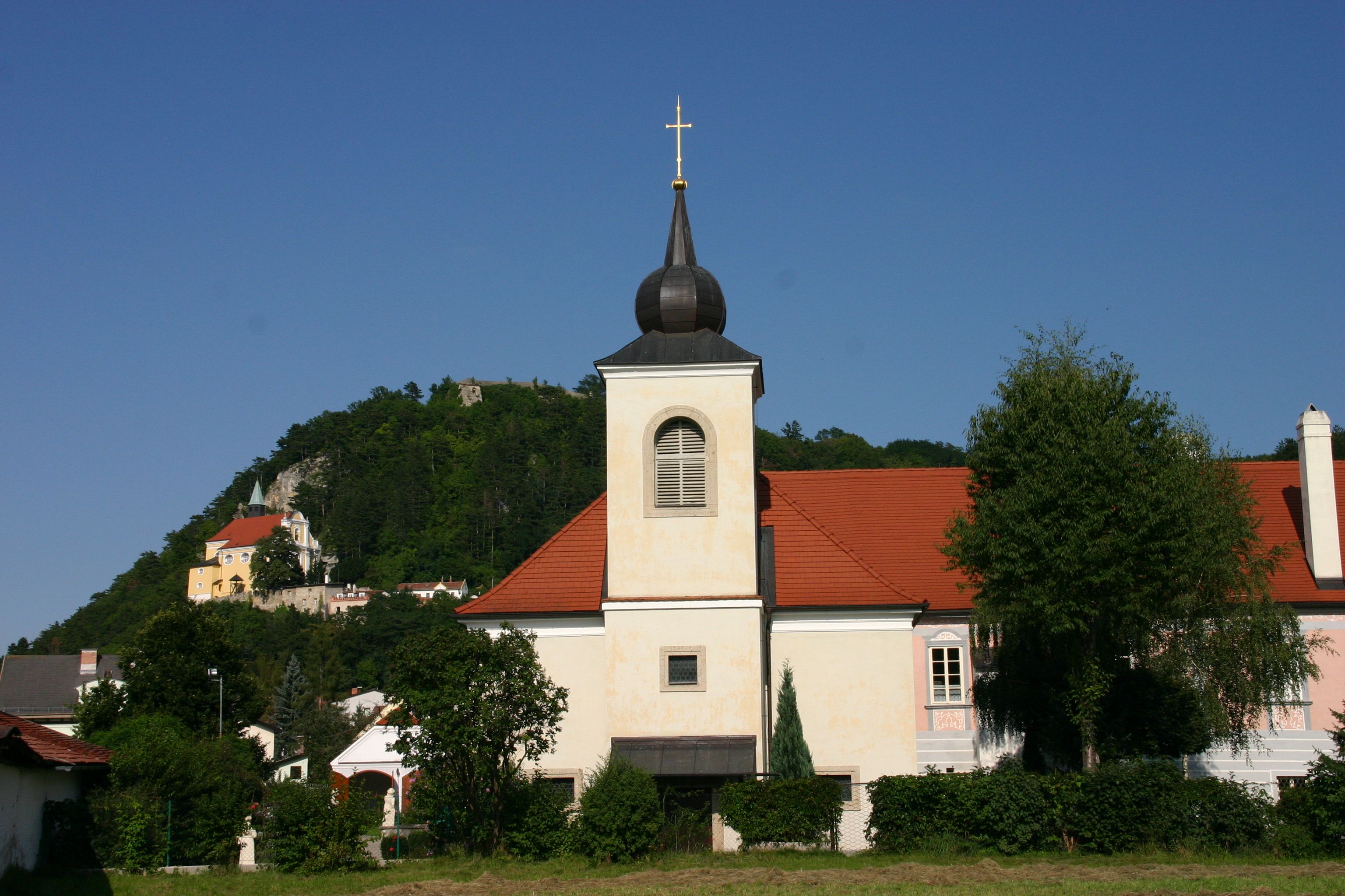 Pitten plébánia a templommal és a dombdal a háttérben.