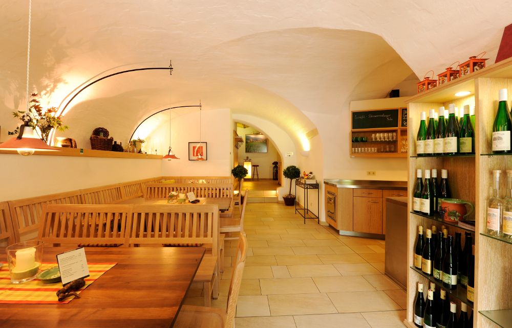 Belső nézet egy hangulatos borozóról, faasztalokkal és bortartókkal.