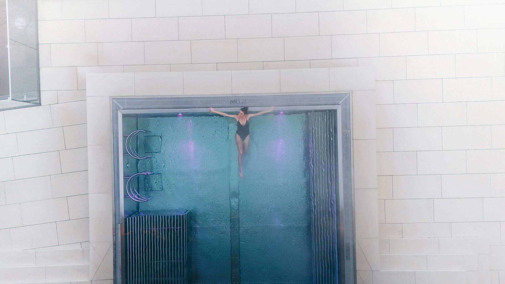 In einem eleganten, glasklaren Pool schwebt eine Person, umgeben von sanften Lichtern, die eine beruhigende Atmosphäre schaffen. Die harmonische Verbindung von Wasser und Licht lädt dazu ein, die Seele baumeln zu lassen und die Schönheit der Umgebung zu genießen.