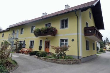 Sárga kétszintes ház erkéllyel és kerttel.