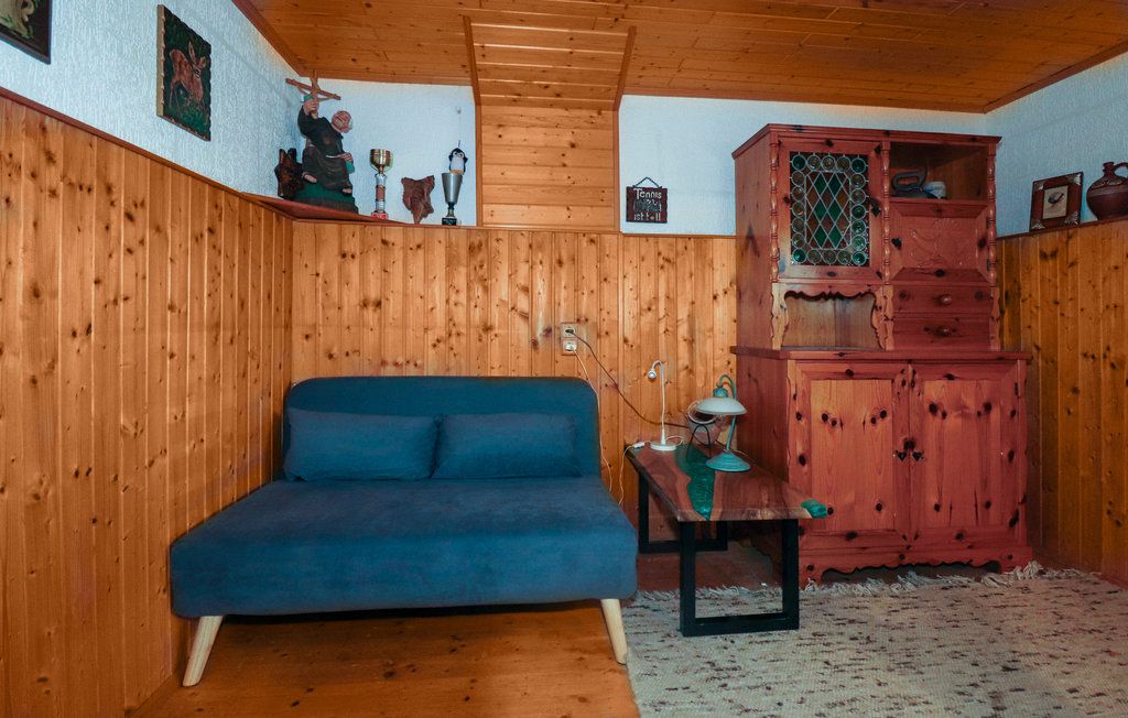 Hangulatos szoba fából készült falakkal, kék kanapéval, fa asztallal és rusztikus szekrénnyel.