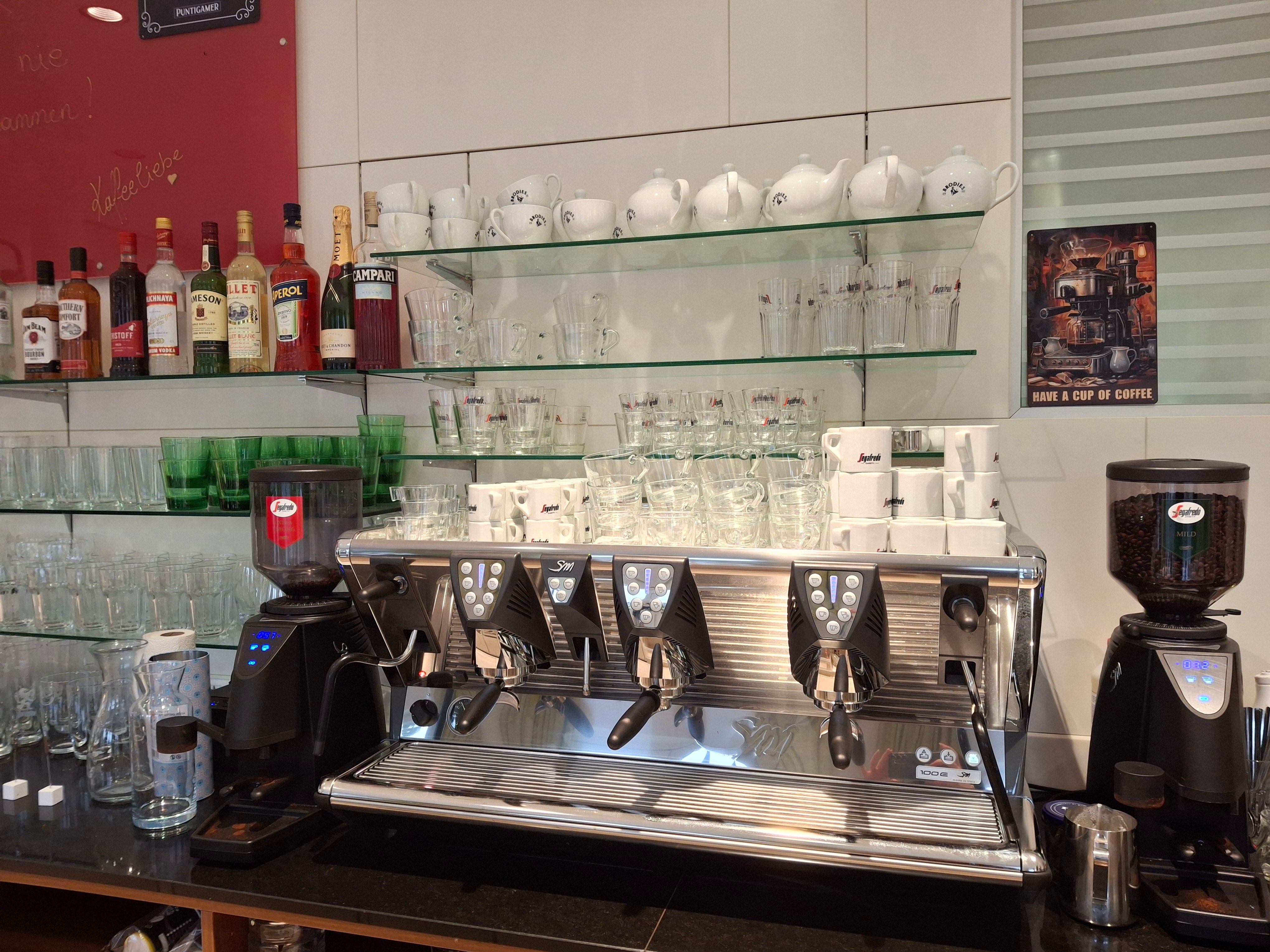 Kávégép csészékkel és poharakkal egy kávézóban.