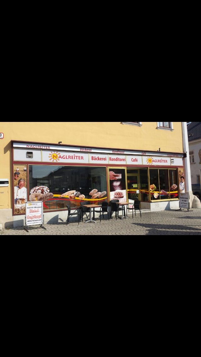 A Café-Bäckerei Naglreiter külső nézete, asztalokkal és székekkel az üzlet előtt.