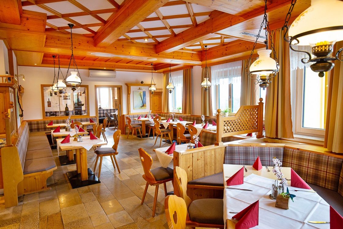 Hangulatos étterem fabútorokkal és terített asztalokkal.