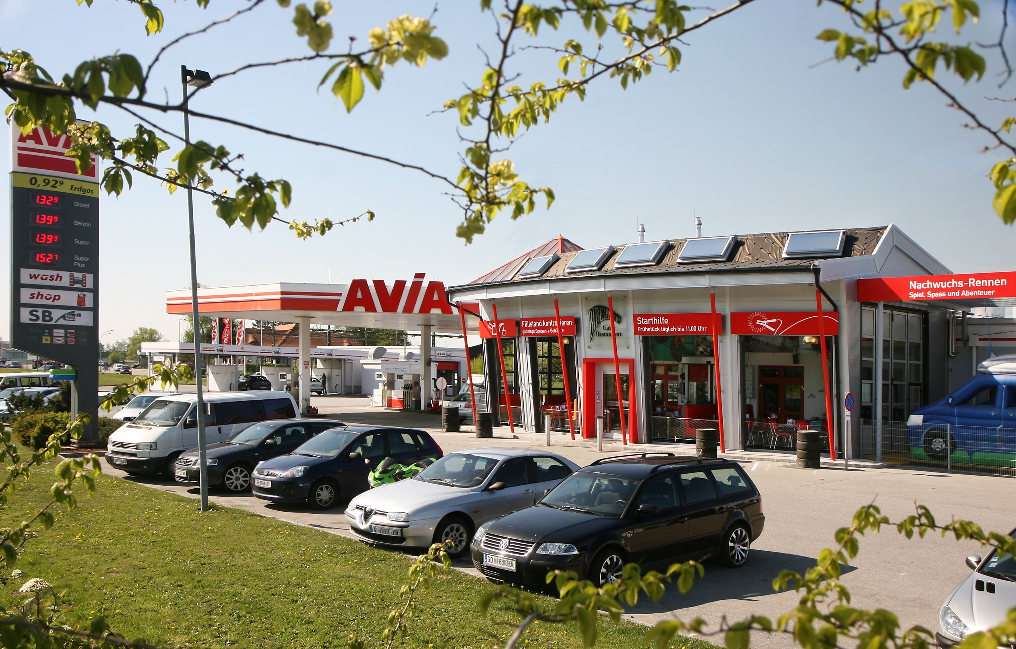 Benzinkút AVIA logóval és több parkoló autóval az előtérben.