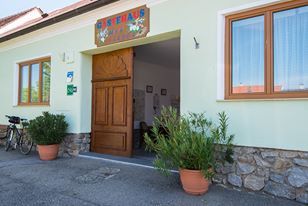Egy épület bejárata faajtóval és cserepes növényekkel.