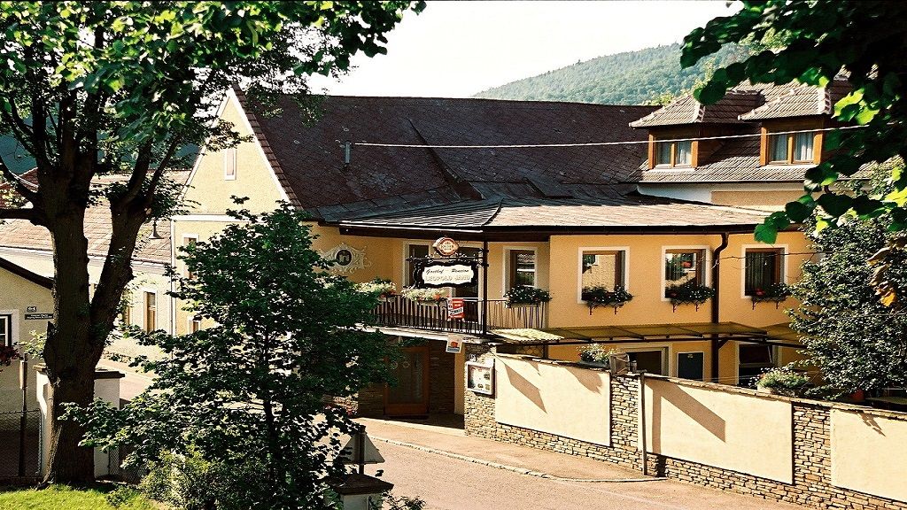 A Leopold Janu panzió külső nézete sárga homlokzattal és virágládákkal.