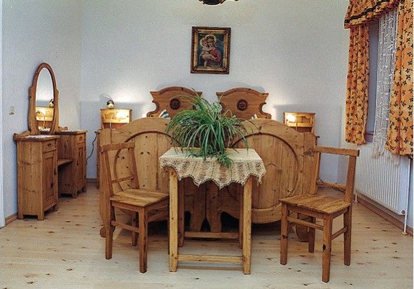 Rusztikus hálószoba fából készült bútorokkal, franciaággyal, asztallal és tükörrel.