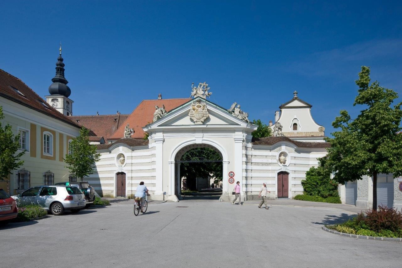Történelmi egyházmegyei épület, a háttérben boltív és templomtorony.