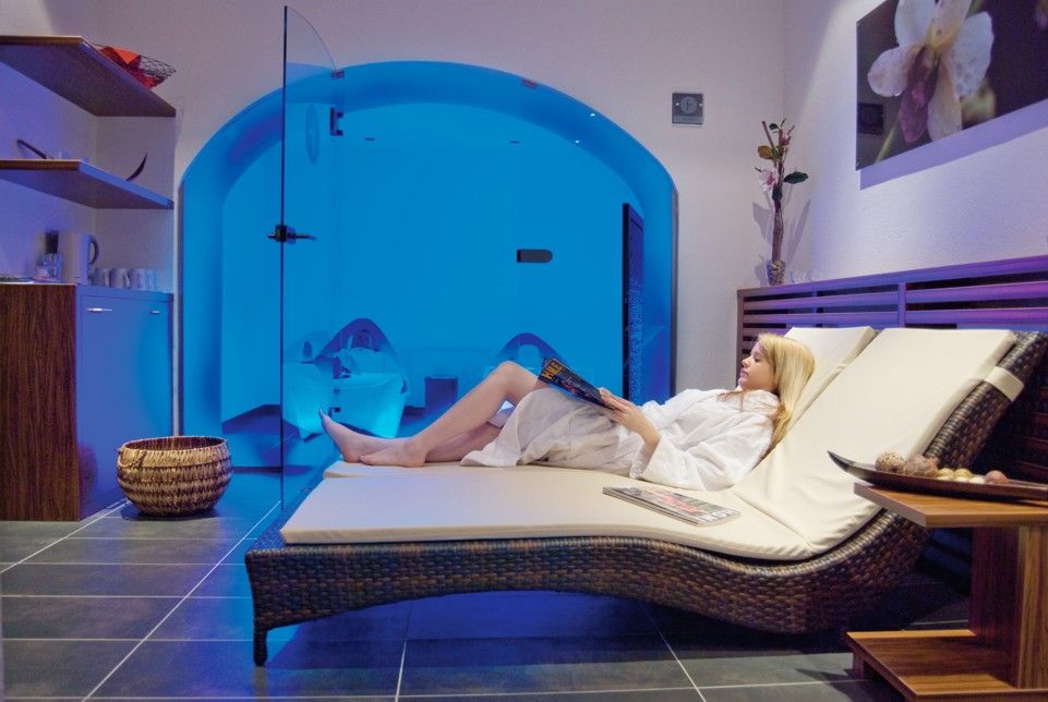 Nő pihen egy nyugágyon a kék világítású wellnessrészlegben.