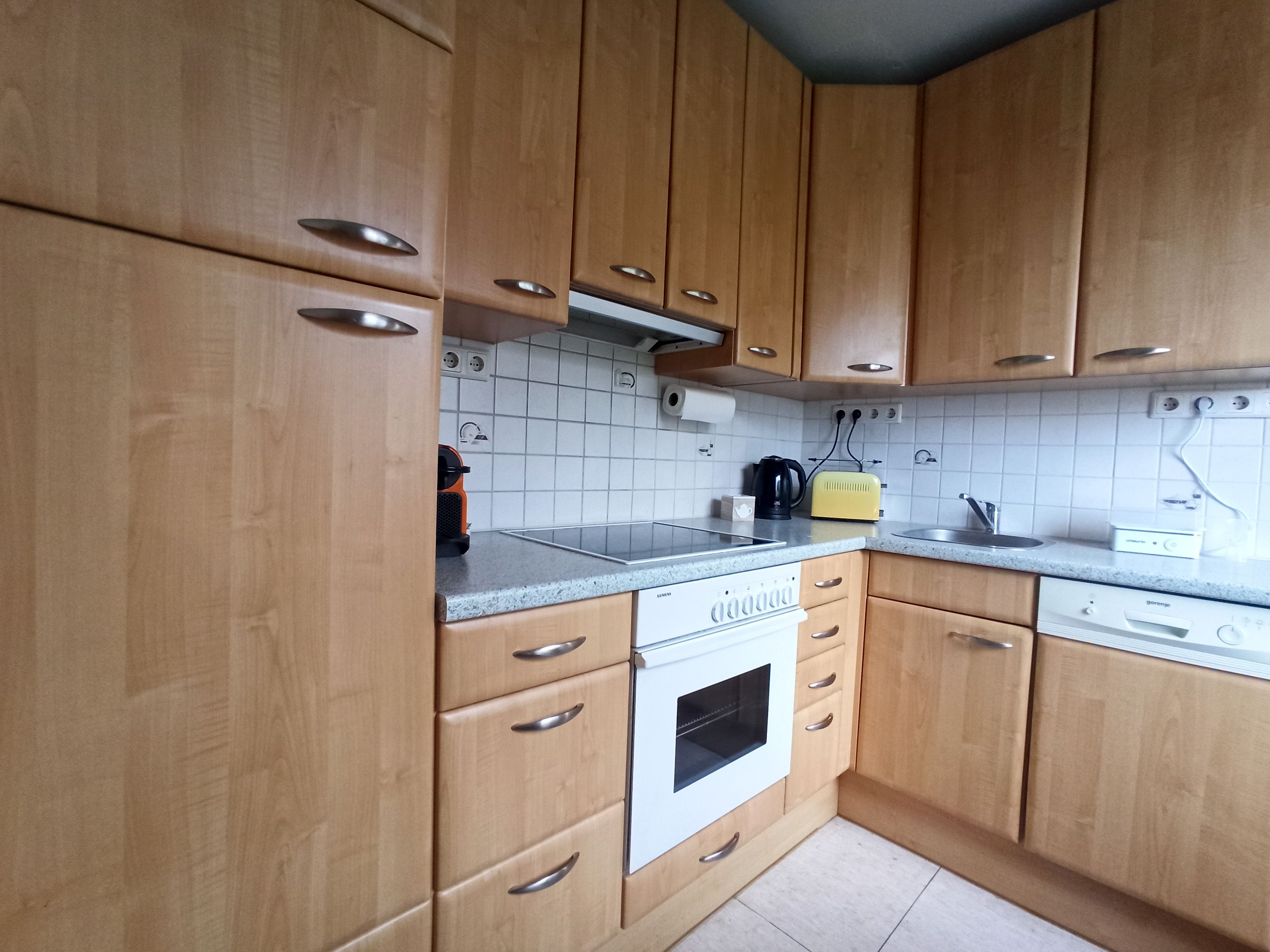 Konyha fából készült szekrényekkel, tűzhely, mosogató és munkalap.