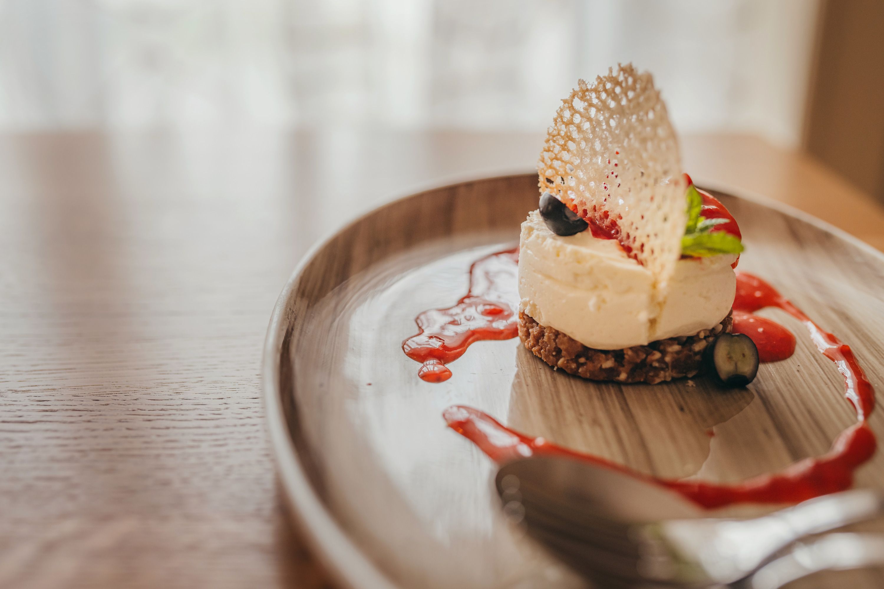 Mini sajttorta epres coulis-szal, tányéron tálalva.