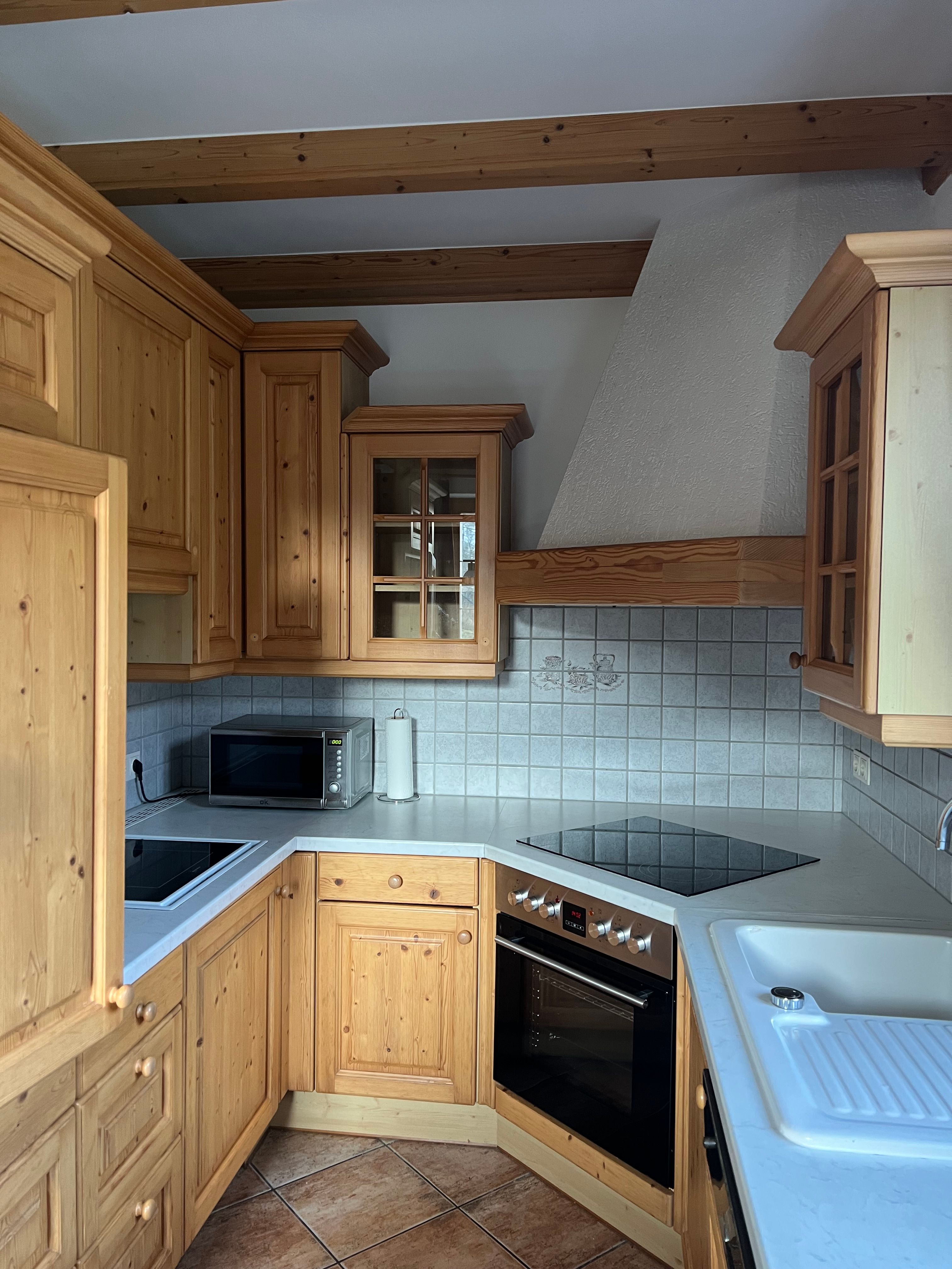 Rusztikus konyha fából készült szekrényekkel, elektromos tűzhely, mikrohullámú sütő és mosogató. A falak csempézettek.