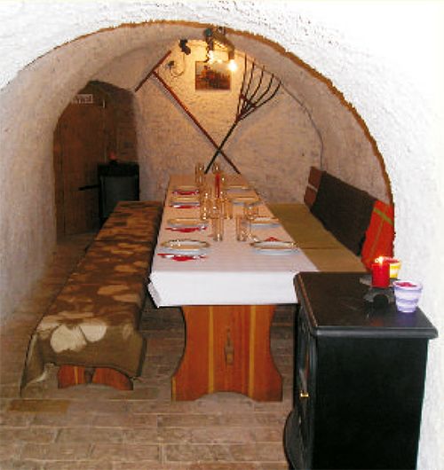 Hangulatos borospince terített asztallal és rusztikus berendezéssel.